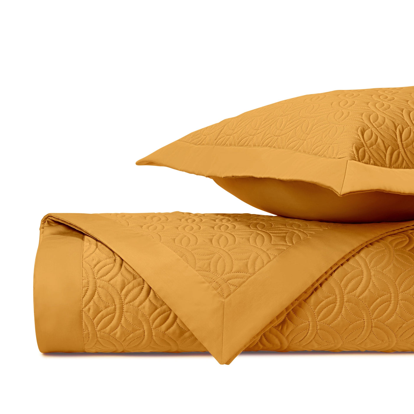 Duomo quilted coverlet and sham in marigold, showing geometric floral stitching pattern.