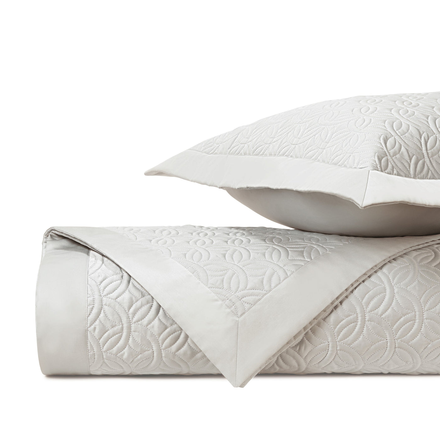 Close-up of ivory quilted cotton with geometric floral stitching pattern and satin border trim.