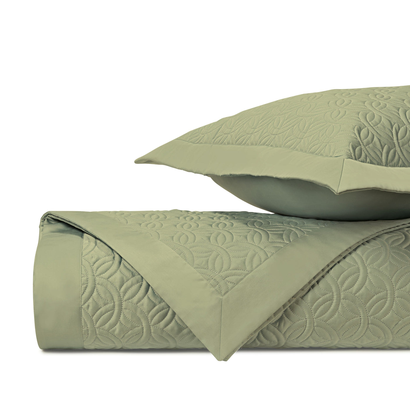 Close-up of sage green quilted coverlet with geometric medallion pattern and matching sham.