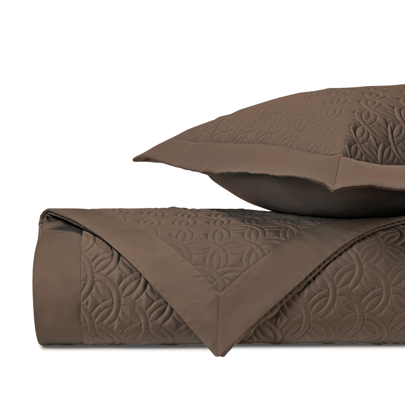 Close-up of Duomo quilted coverlet in mink, showing geometric embroidered pattern and folded edge.