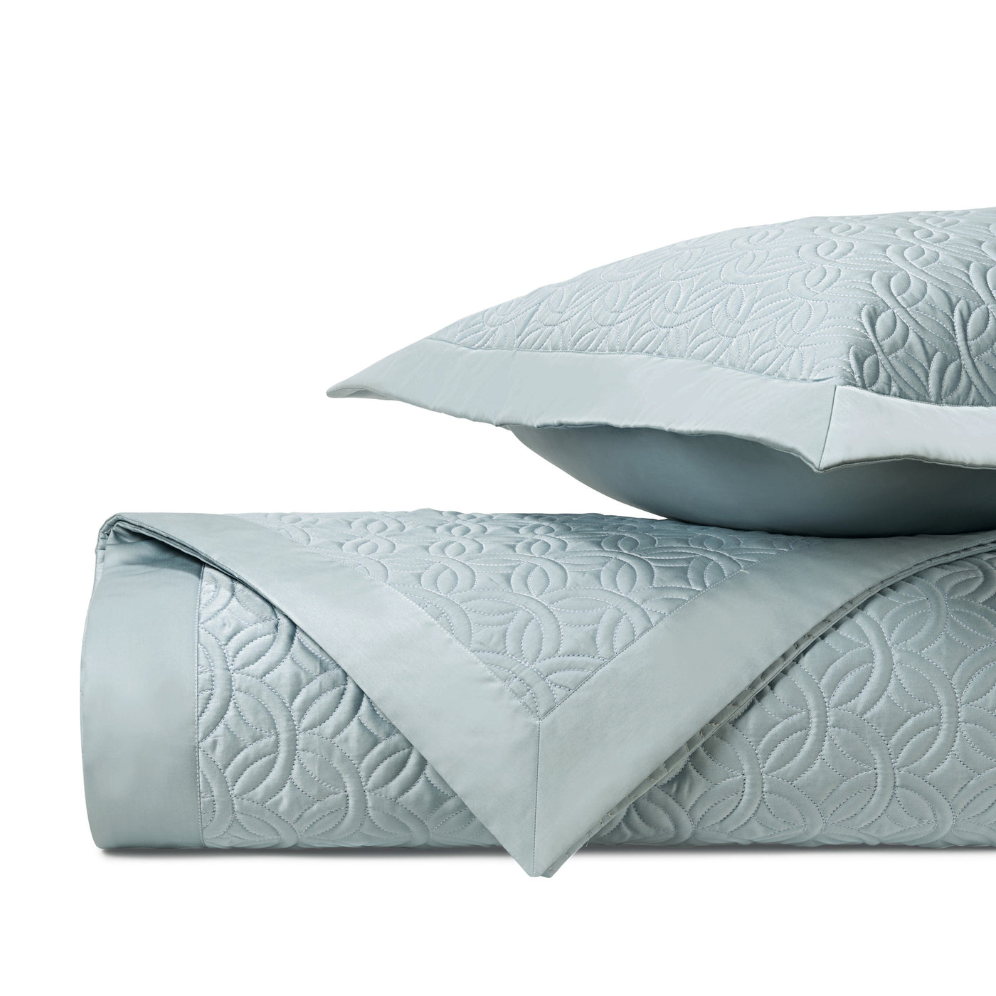 Folded Duomo coverlet in mist blue with geometric quilted pattern, sham stacked behind.