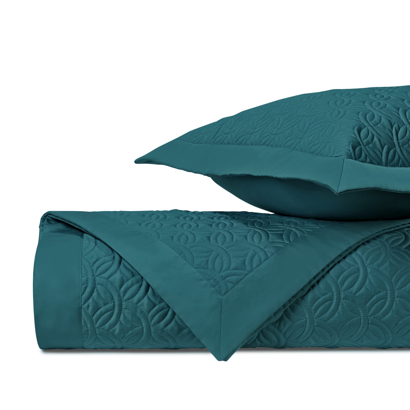 Close-up of teal quilted fabric with geometric medallion stitching pattern.