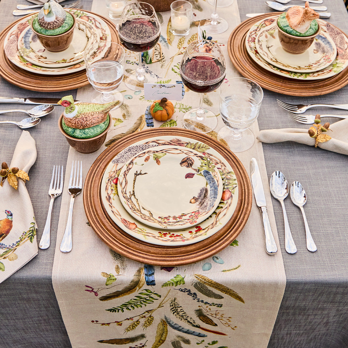 Forest Walk table runner under place settings of Forest Walk plates on wicker chargers