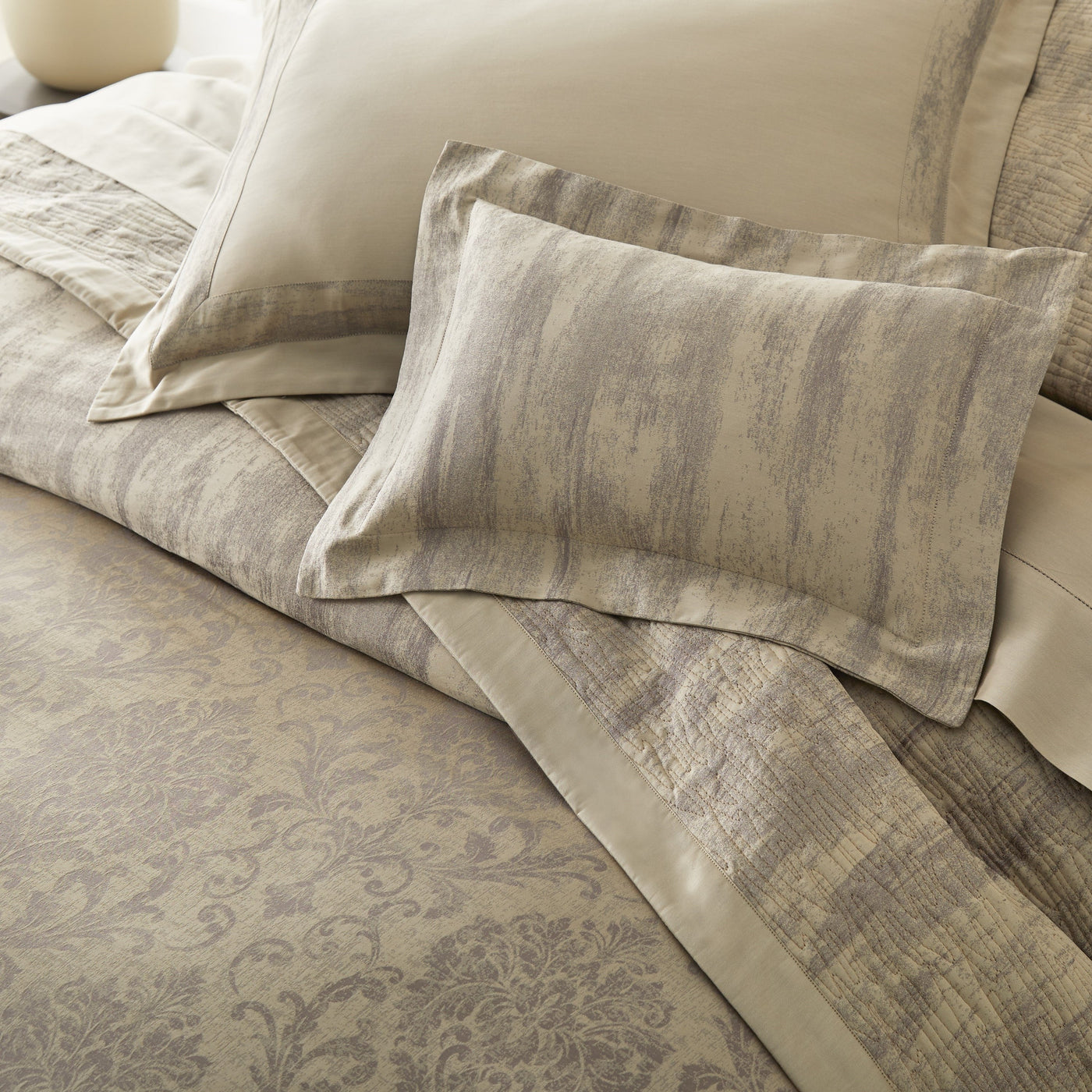 Close-up of Home Treasures Eloise damask pattern in taupe and champagne tones on bedding.