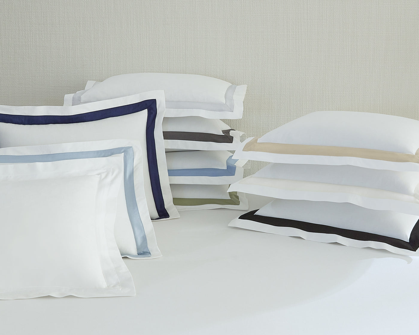 Sferra Estate pillow shams stacked in multiple colors on white bedding.