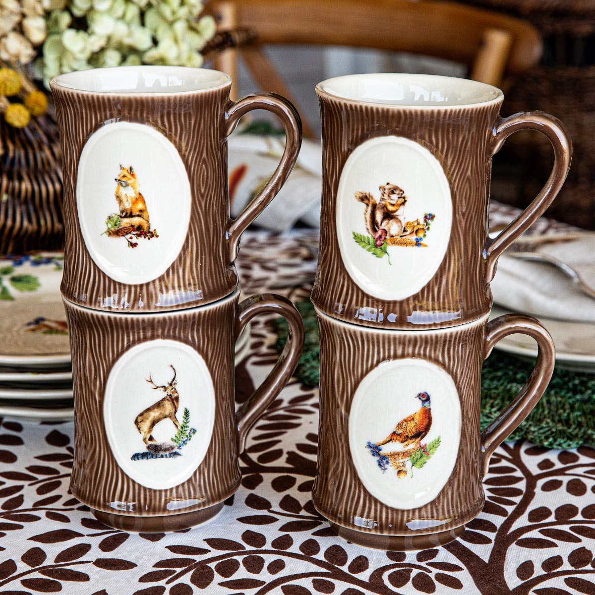 Four Forest Walk animal mugs stacked in two rows on a brown and white patterned cloth