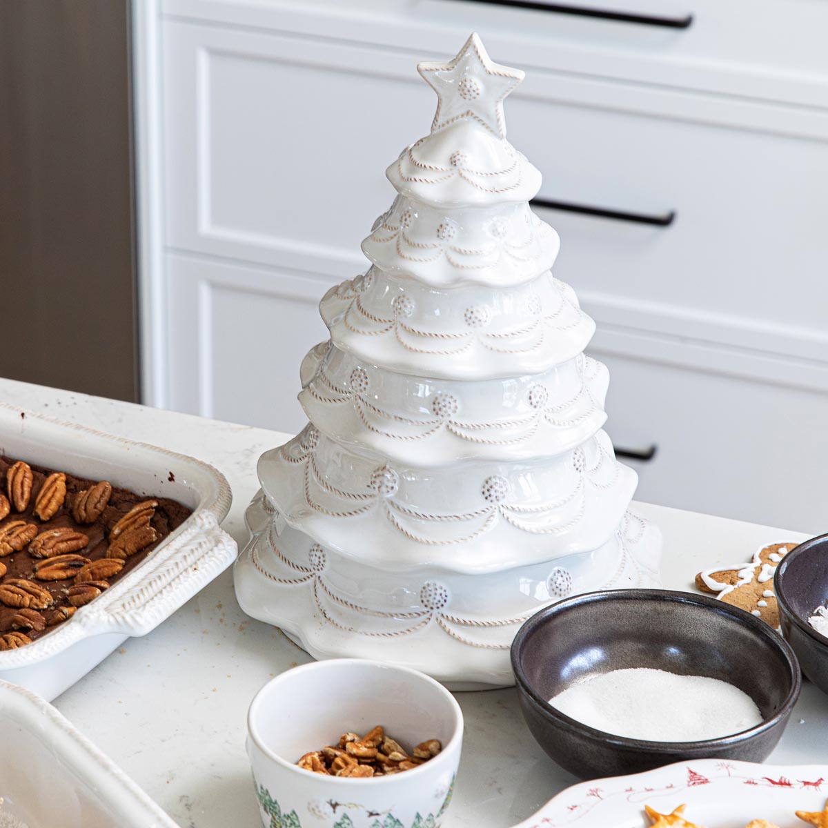 Whitewash Christmas tree cookie jar on a kitchen counter beside baking dishes