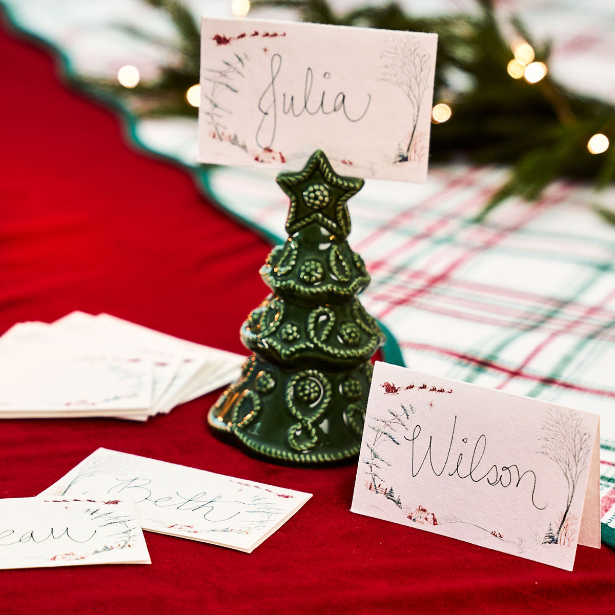Winter Frolic place cards with handwritten names beside a green tree place card holder