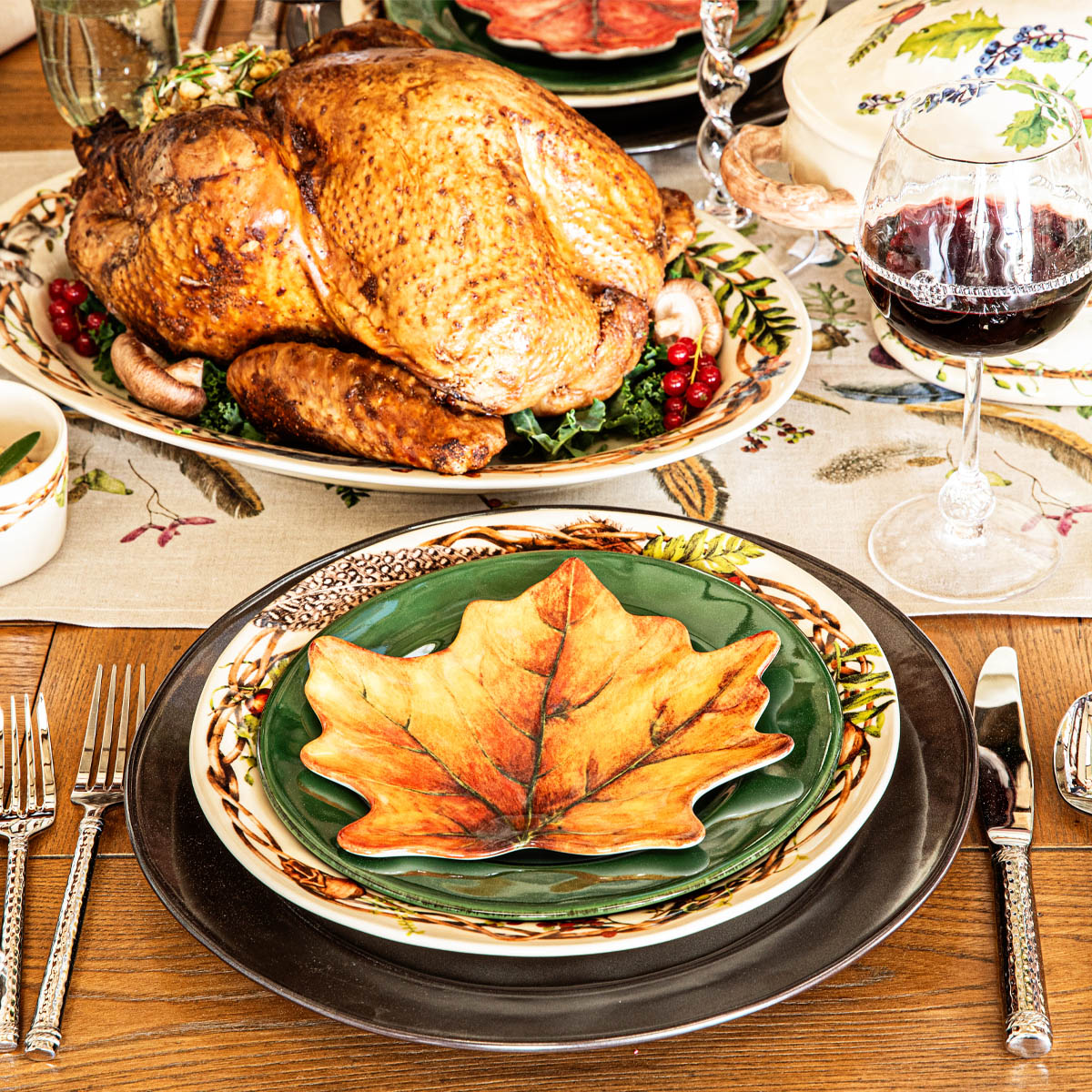 Orange maple Forest Walk leaf plate on a place setting with a roast turkey and red wine behind