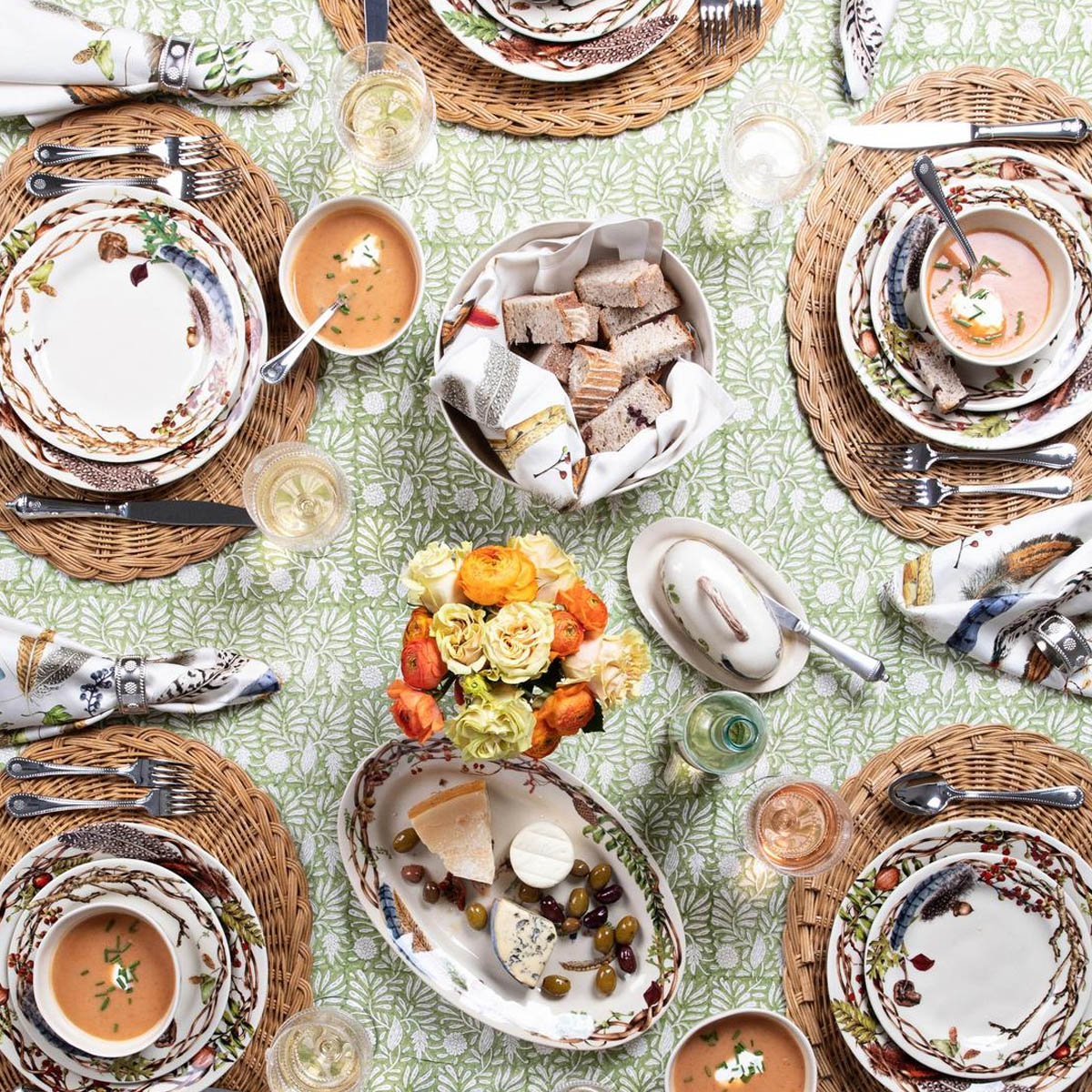 Overhead of a table set with Forest Walk dinnerware, soup and napkins on a green leaf tablecloth