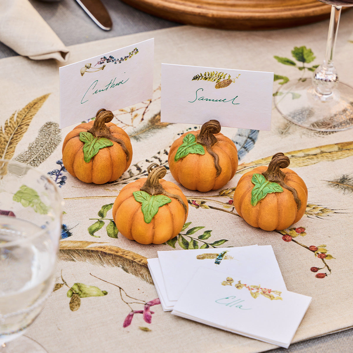 Forest Walk place cards on pumpkin holders on a feather print tablecloth