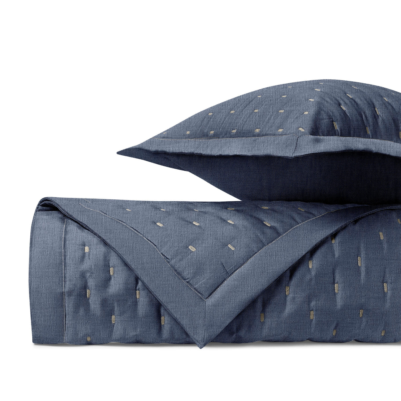 Folded navy quilted coverlet with gold dash embroidery and matching euro sham, corner detail visible.