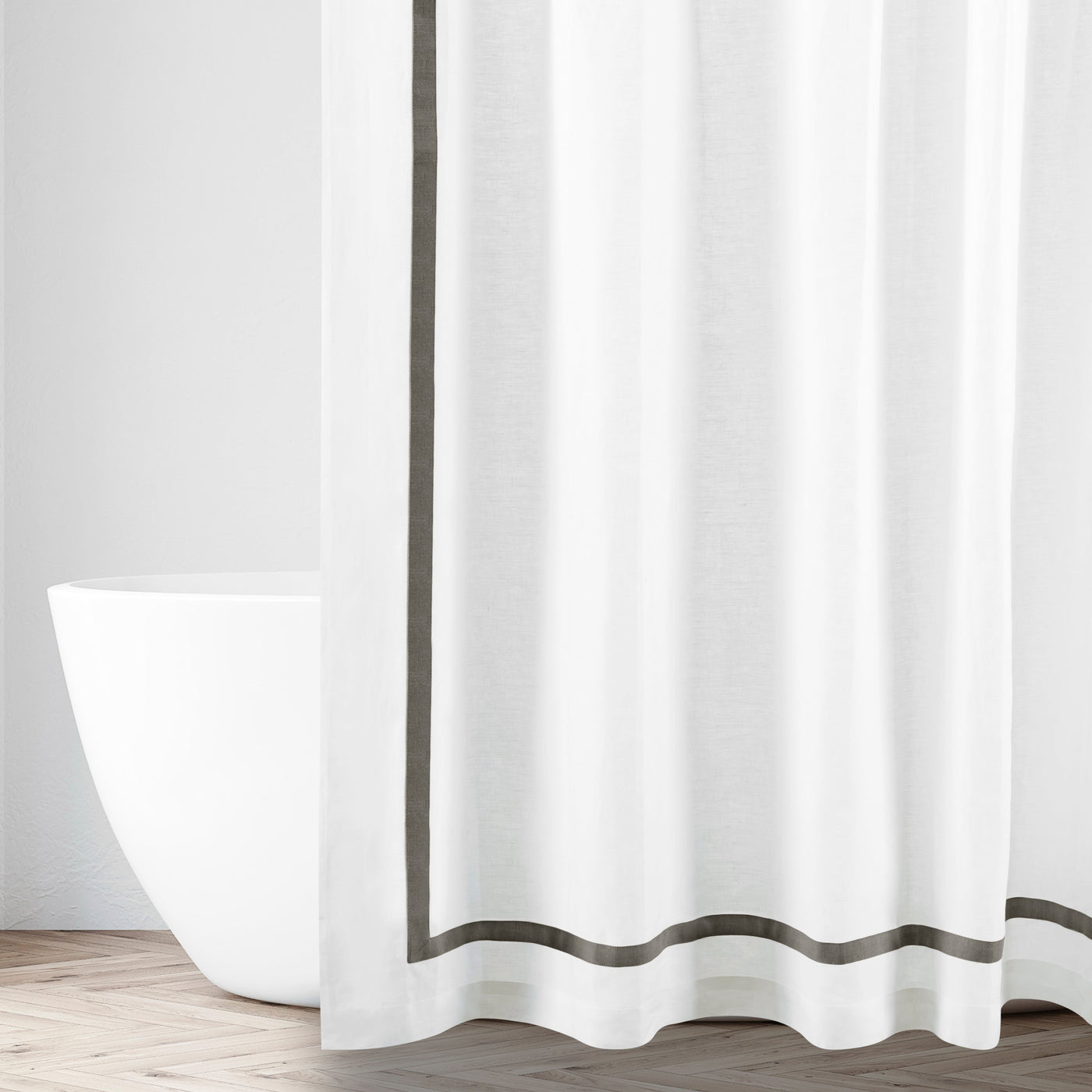 White linen shower curtain with charcoal border trim, styled in a bright bathroom setting.