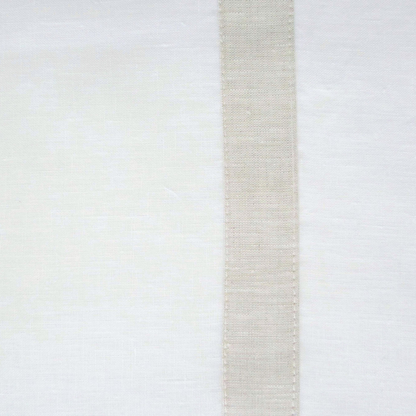 Close-up of a ivory linen placemat with a natural center stripe and stitched border detail.