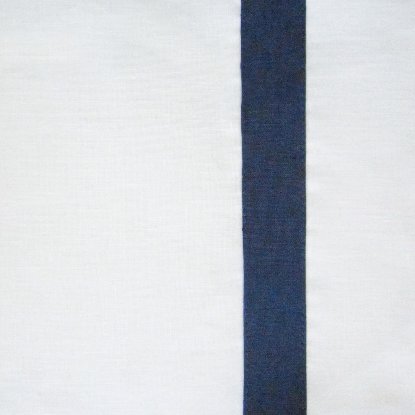 Close-up of navy grosgrain ribbon border detail on white linen fabric.