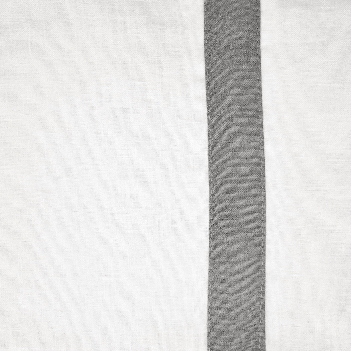 Close-up of charcoal linen band with blanket-stitch edging on white linen tablecloth.