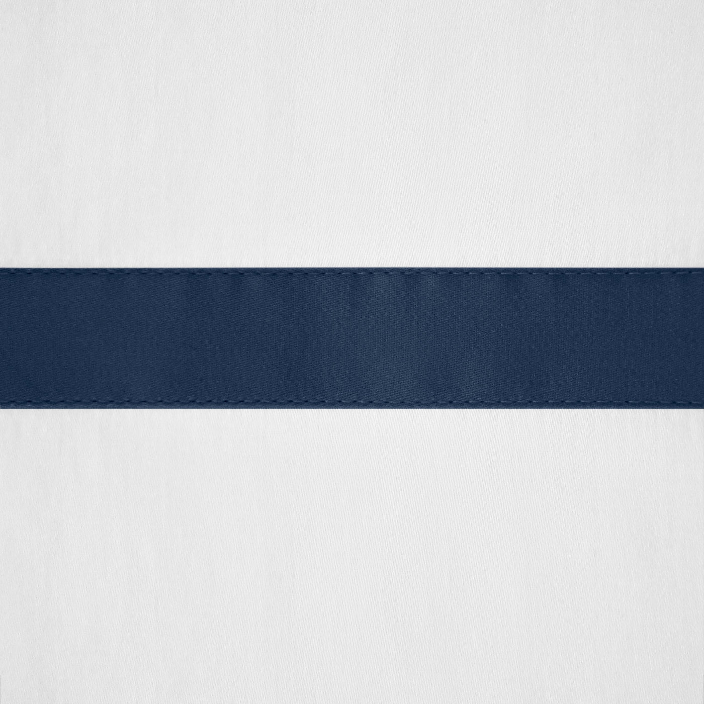 Close-up of navy satin border detail against white linen fabric.