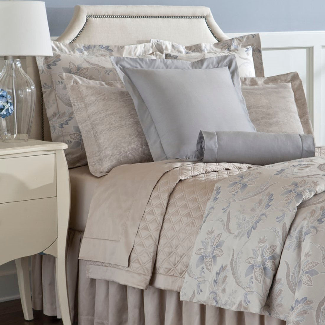 Close-up of Fiori pillowcase with blue and ivory floral jacquard pattern on linen bedding display.