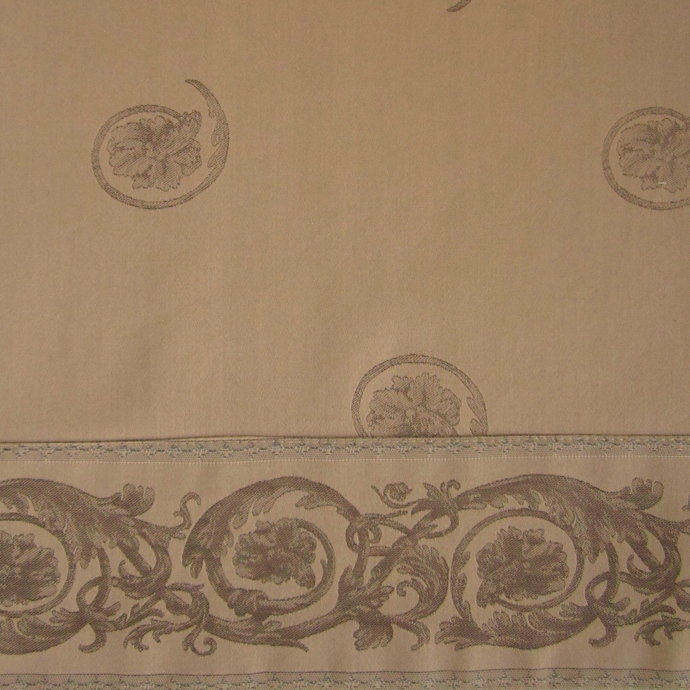 Close-up of champagne fabric with tone-on-tone baroque floral medallions and scrollwork border.