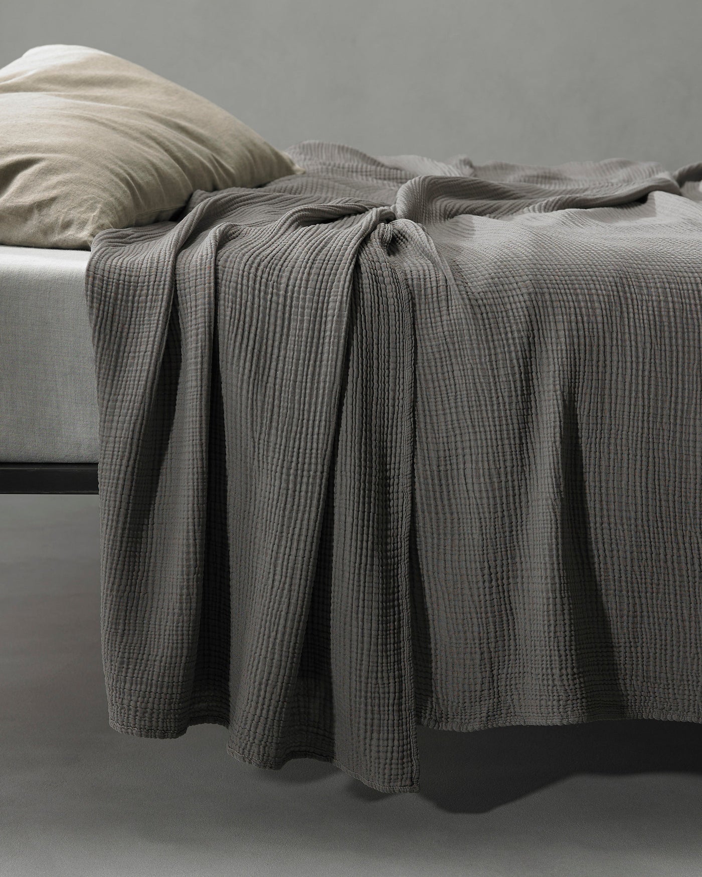 Close-up of Society Limonta Free New bedcover in slate grey waffle texture draped over bed edge.