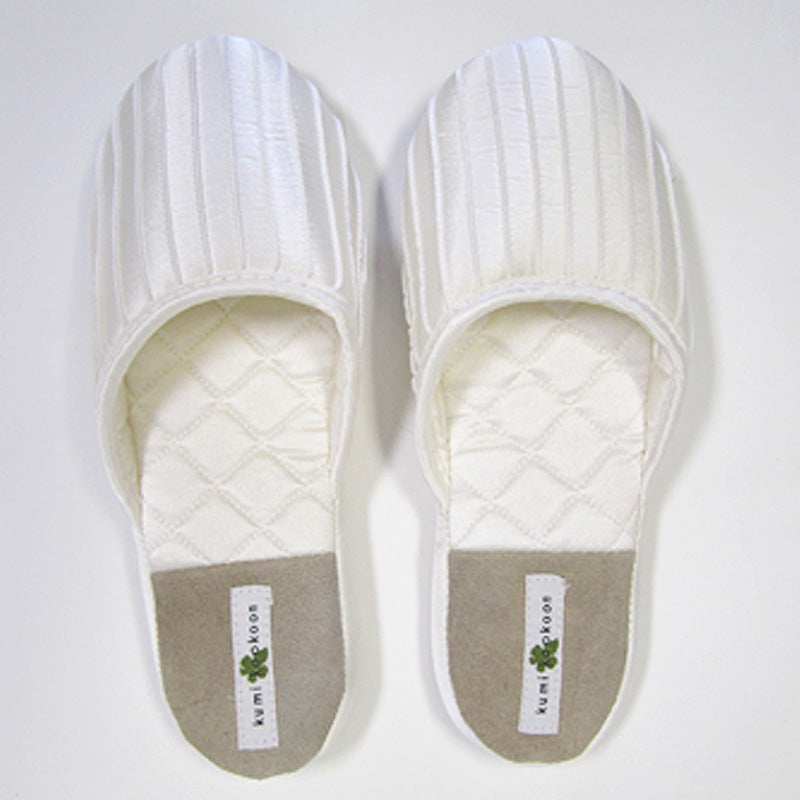 A pair of white Kumi Kookoon French Pleat Silk Slippers with gray heel patches, side by side on a white background, perfect for a spa-like experience.
