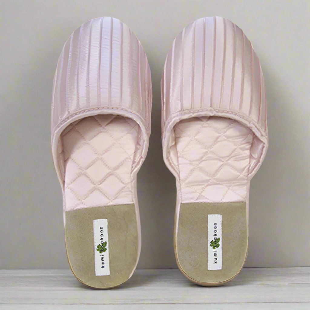 Kumi Kookoon French Pleat Silk Slippers in light pink, featuring quilted uppers and beige soles, are shown side by side on a light surface.