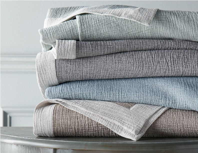 Stack of Home Treasures Atacama throws folded in mist, silver, and taupe colorways.