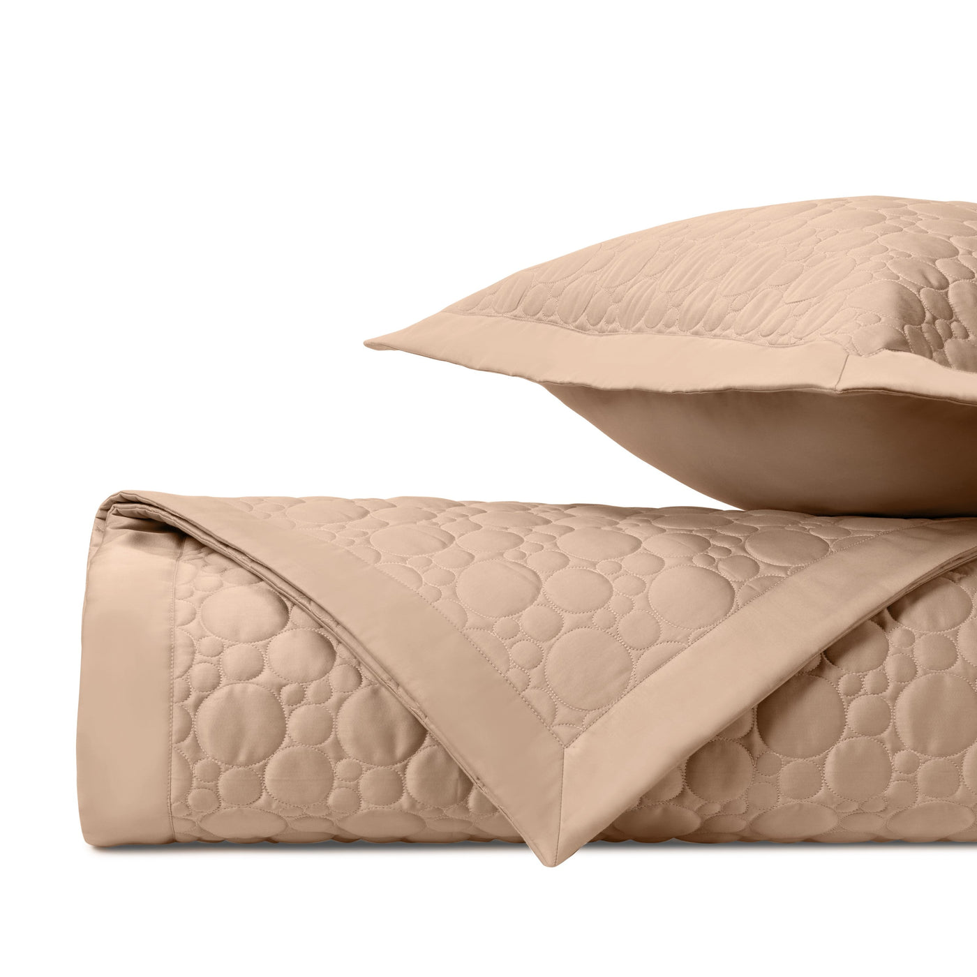 Close-up of camel quilted fabric with circular stitching pattern and bordered edge.