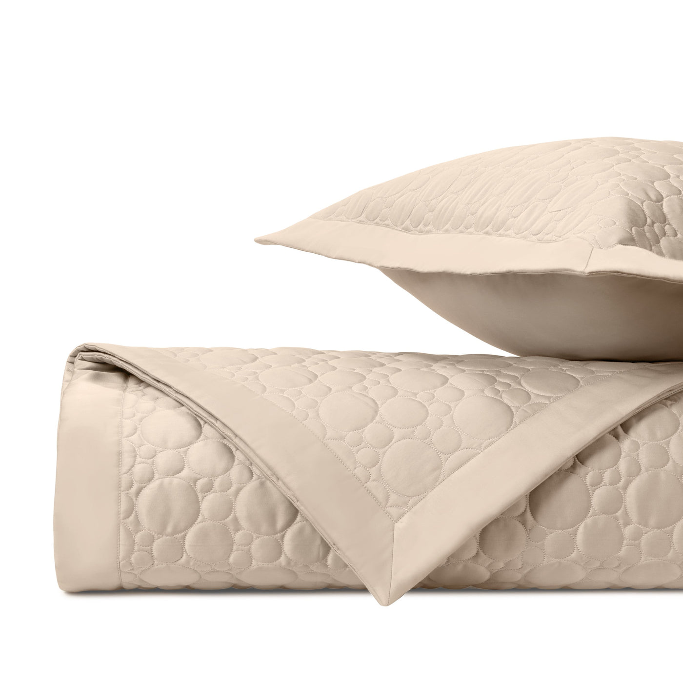 Close-up of champagne quilted fabric with circular medallion stitching pattern and flat border edge.