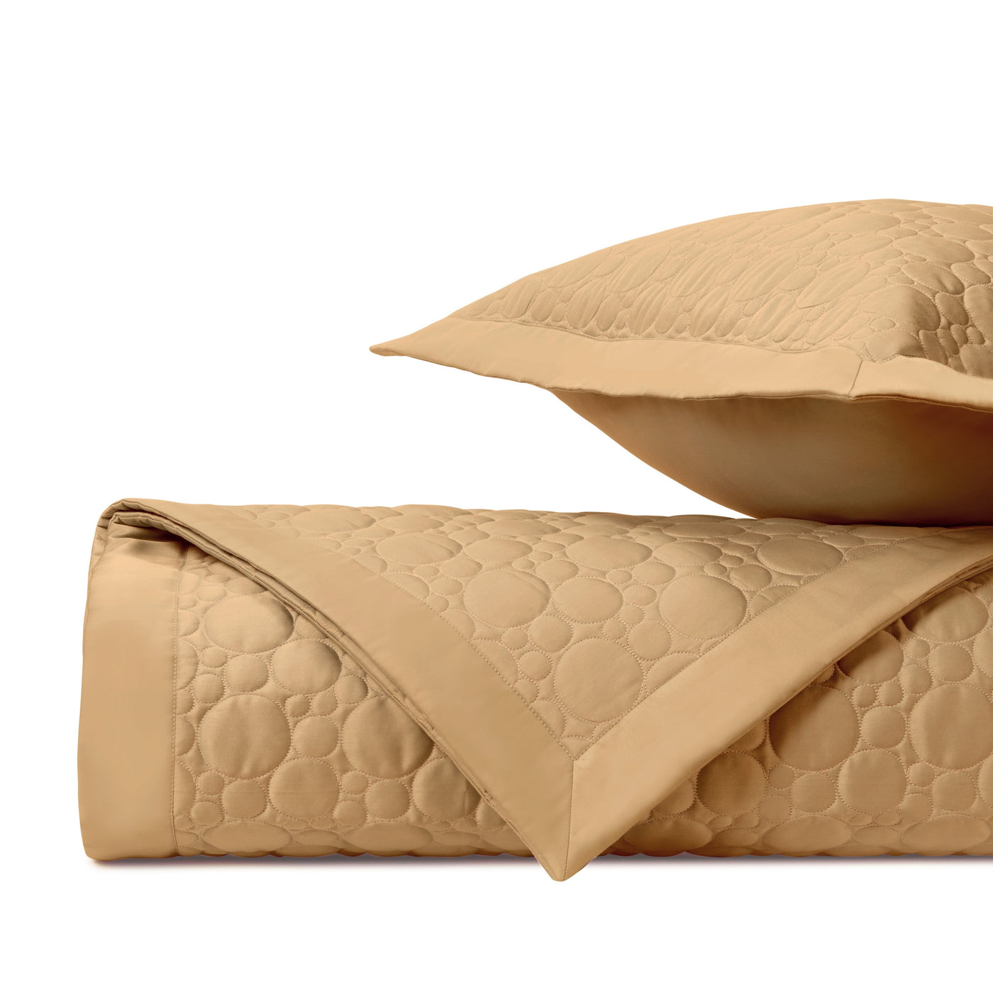 Close-up of Home Treasures Globe quilted coverlet in camel with circle stitching detail.