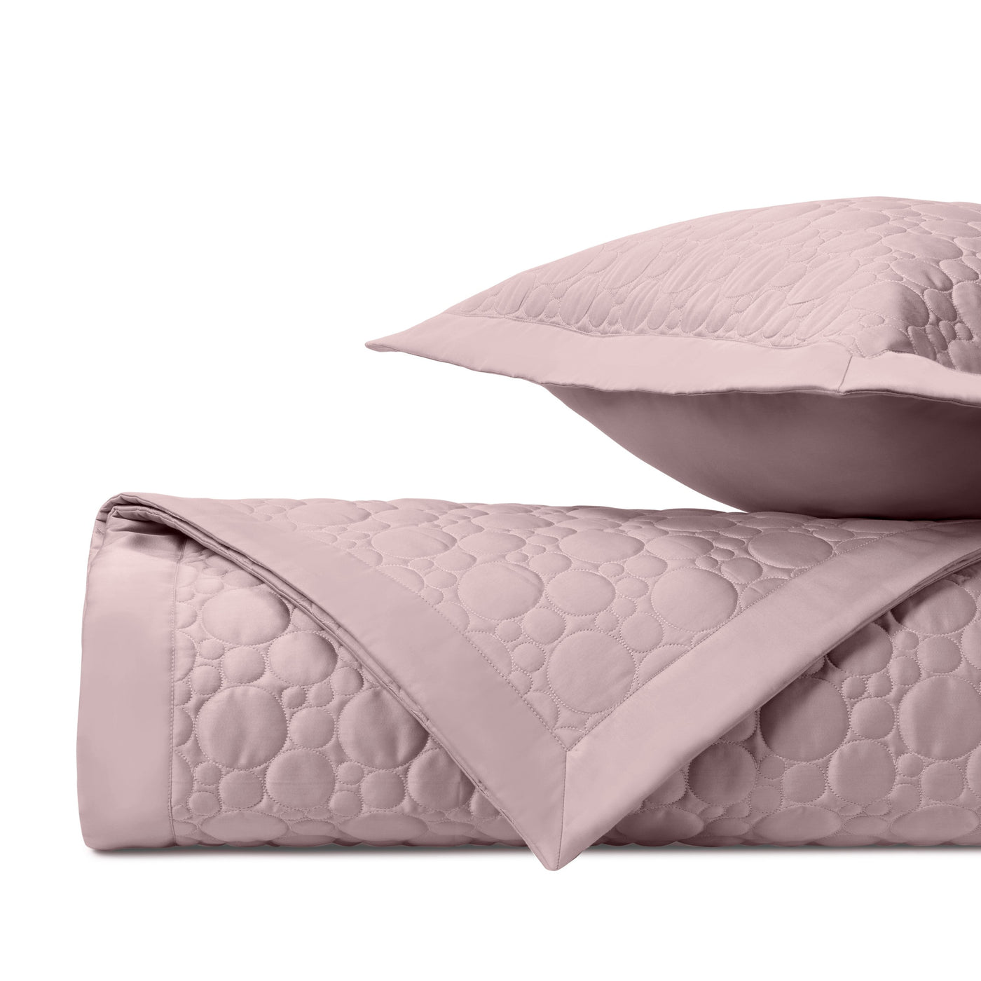 Close-up of Globe quilted cotton in blush pink, showing circular stitch pattern and trim detail.