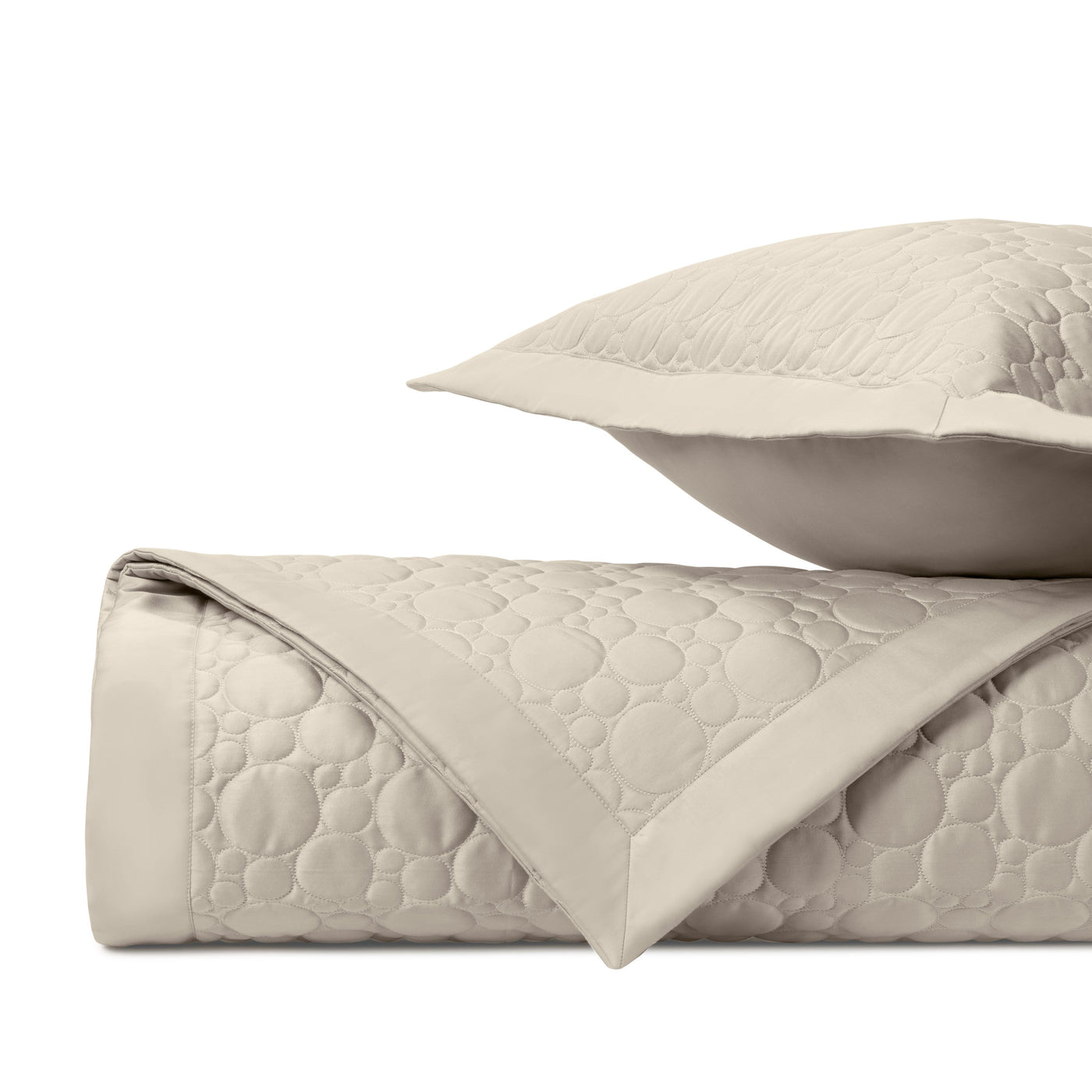 Close-up of ivory quilted fabric with circular stitching pattern and flat border edge.