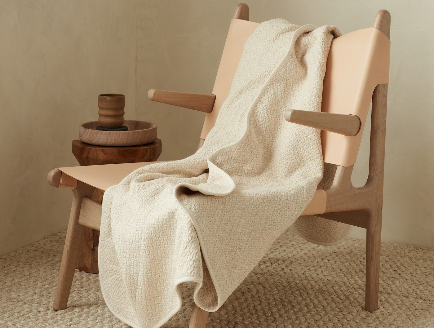 Ivory waffle-weave blanket draped over a natural wood armchair.