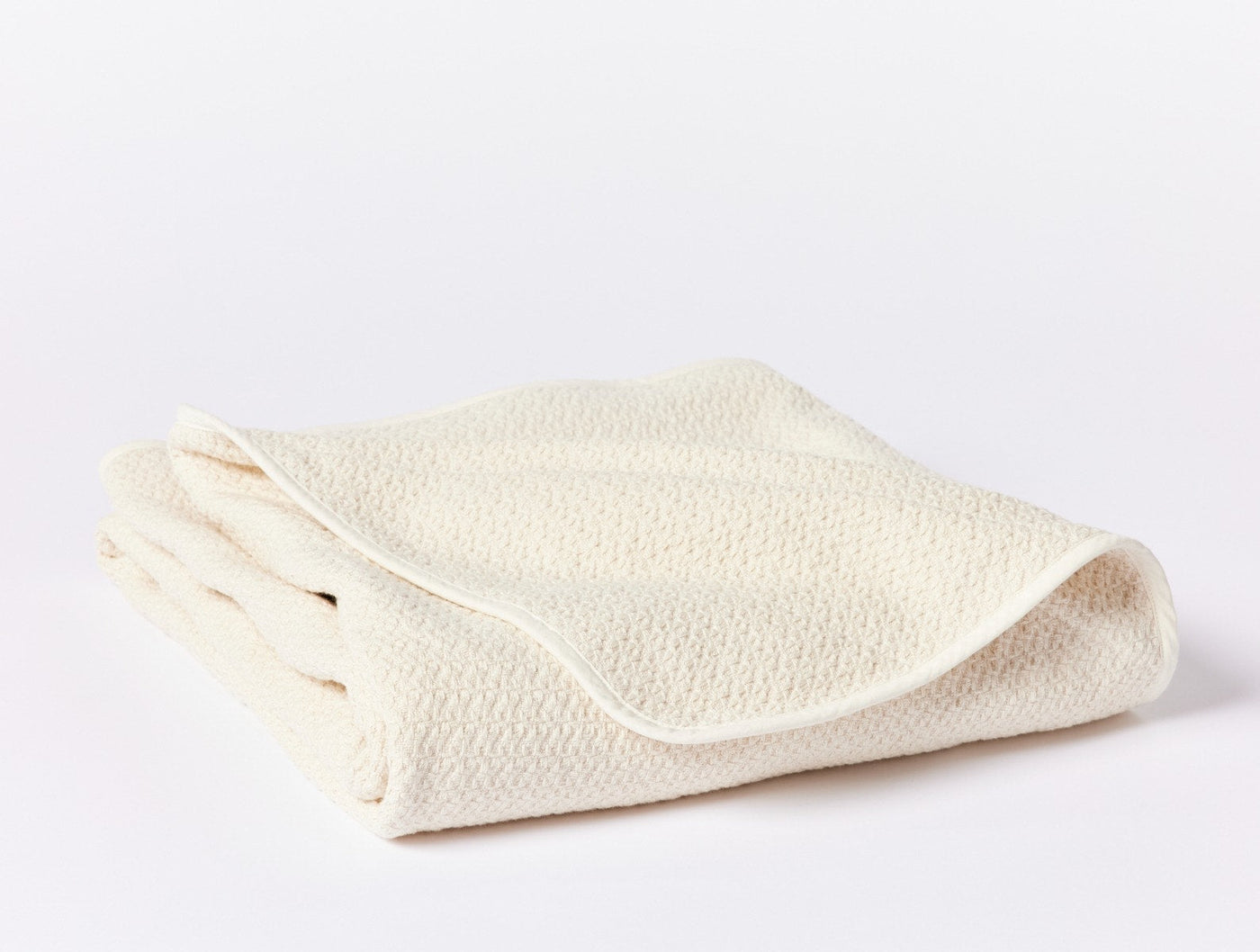 Ivory honeycomb-textured blanket folded to show subtle woven pattern and edge detail.
