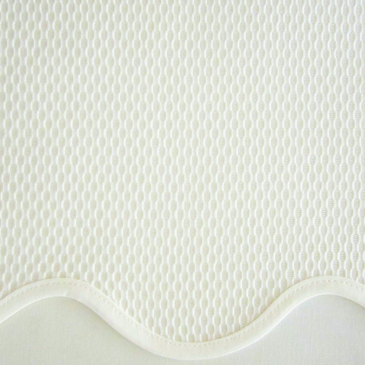 Close-up of ivory honeycomb-weave fabric with scalloped satin border detail.