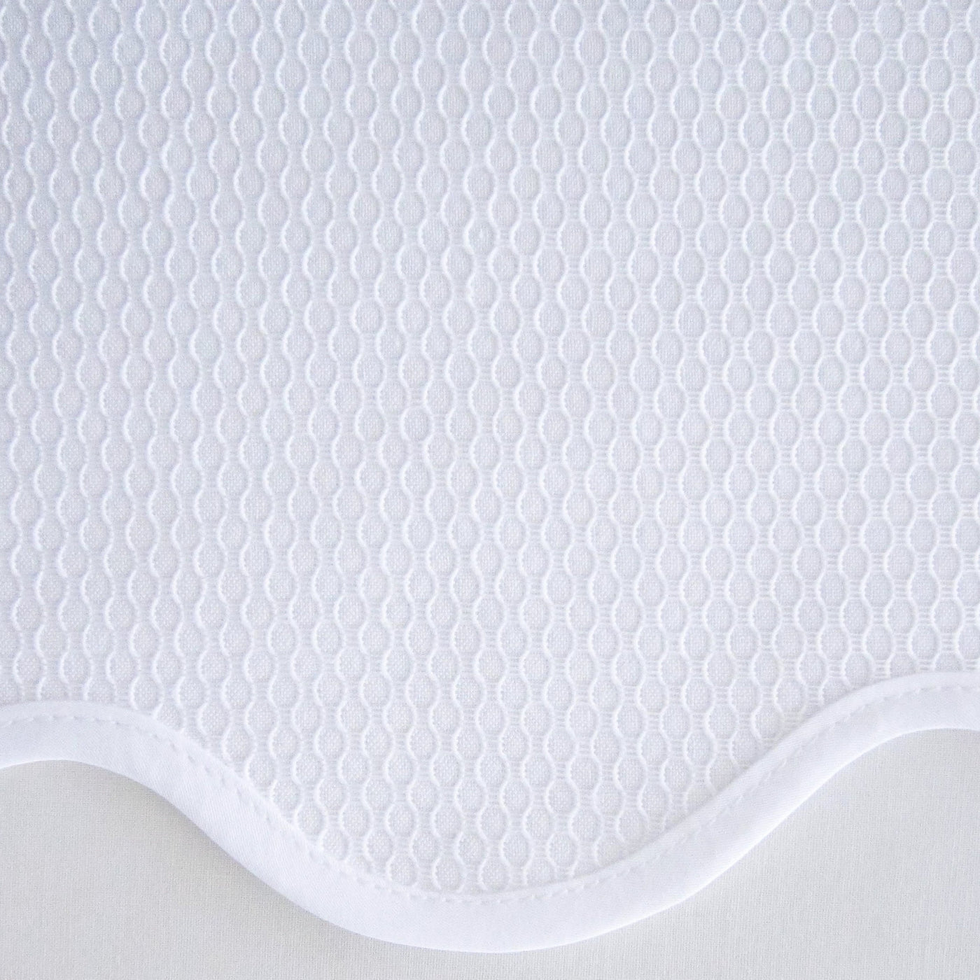 Close-up of white honeycomb-textured fabric with scalloped border detail.
