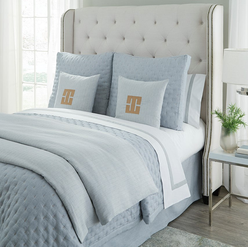 Home Treasures Houston yardage in mist blue on a made bed with quilted coverlet and monogram pillows.