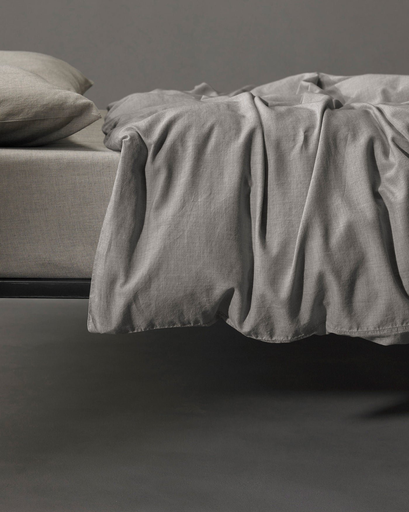 Dove grey linen duvet cover draped loosely over bed foot, showing relaxed texture.
