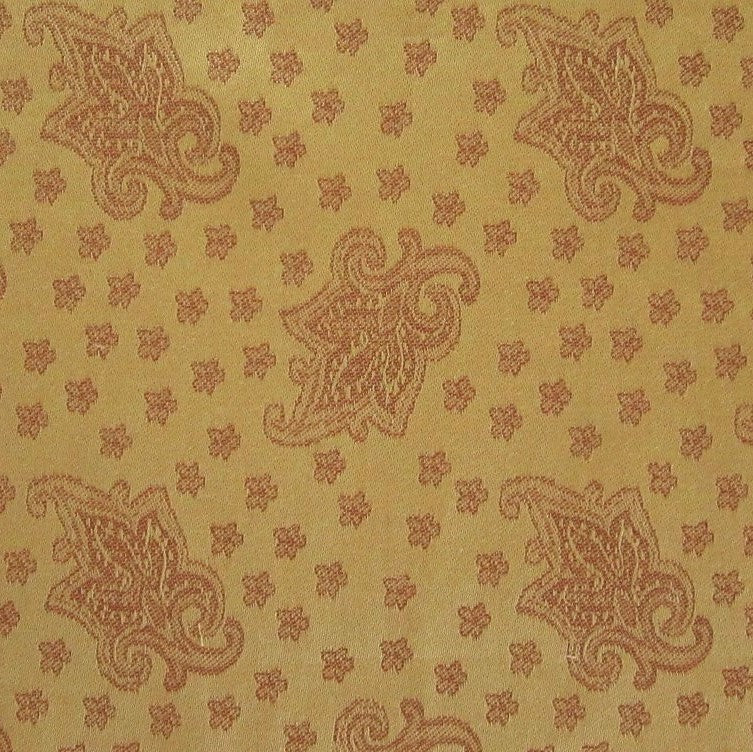 Close-up of gold and terracotta woven paisley and floral jacquard fabric pattern.