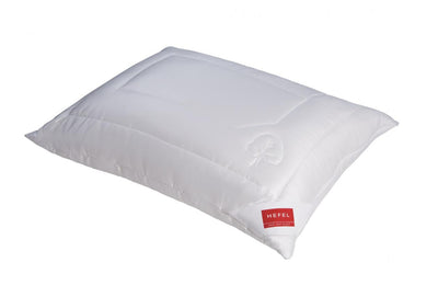 The Hefel Klima Control Comfort Pillow is a white rectangular pillow with a subtle stitched pattern and a red Hefel label, crafted from Tencel bedding for excellent moisture regulation.