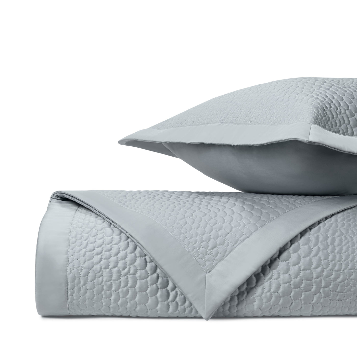 Quilted pebble pattern detail on fog blue coverlet, folded with matching sham.