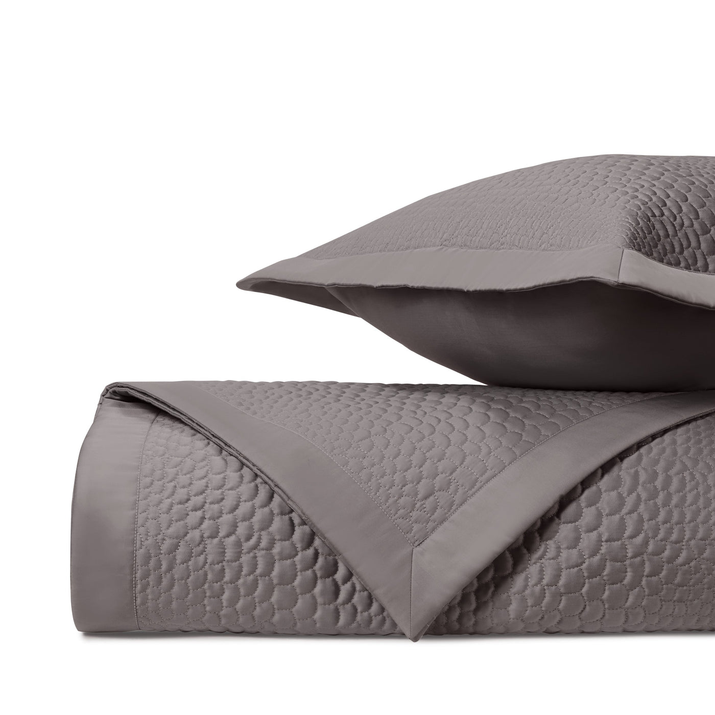 Close-up of Komodo quilted coverlet in graphite with circular stitched pattern.