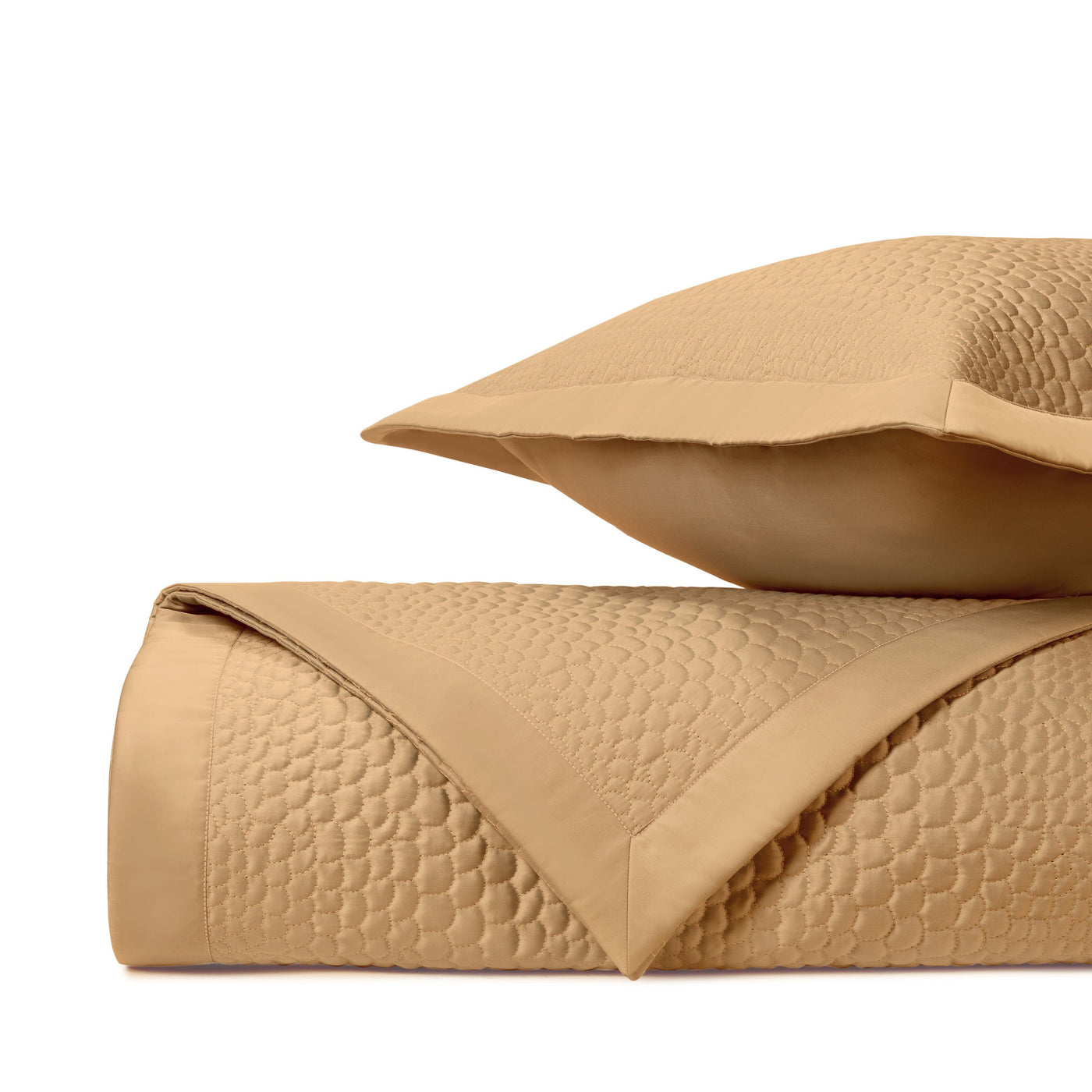 Close-up of Komodo quilted texture in caramel, showing honeycomb stitching pattern on folded coverlet.
