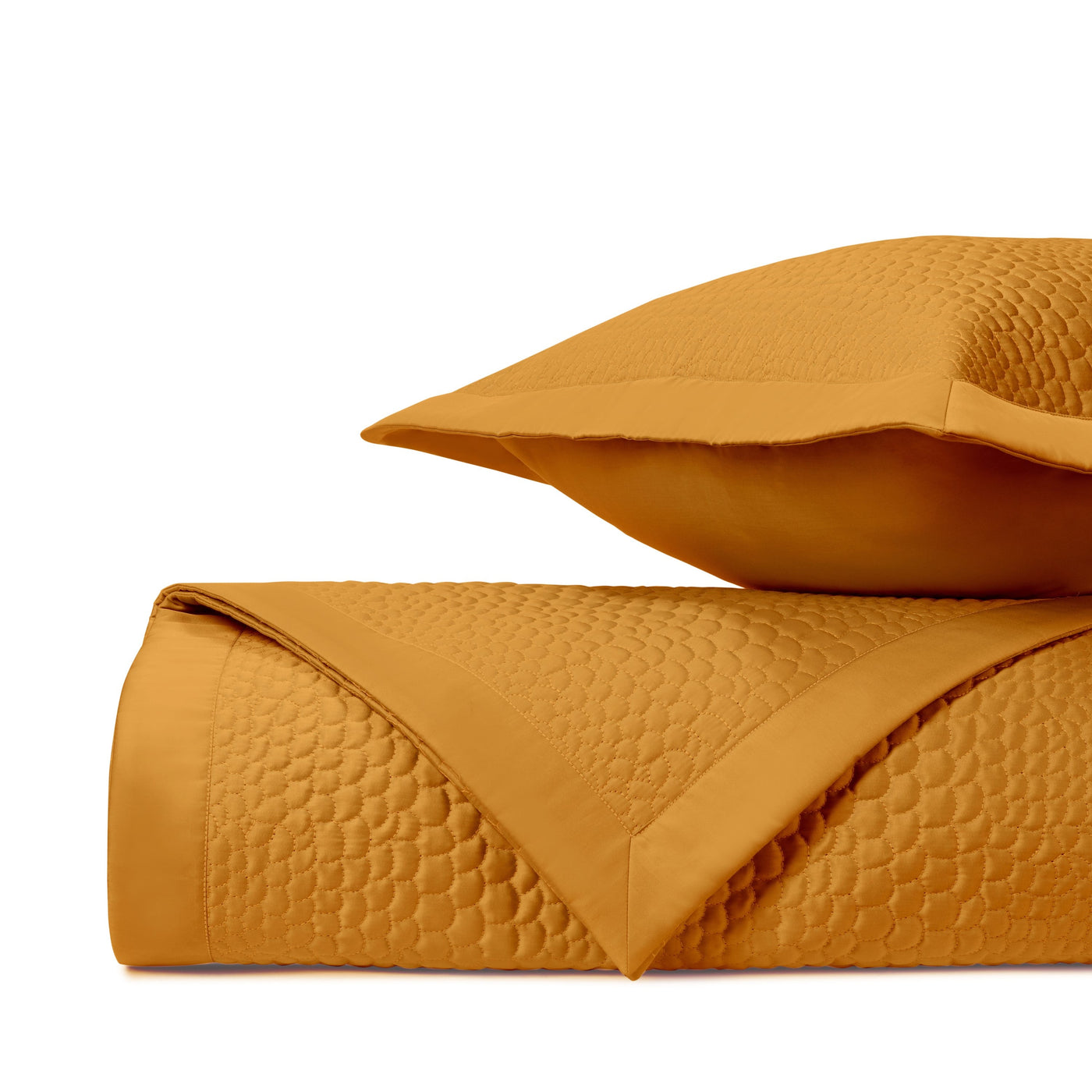 Close-up of saffron quilted cotton with honeycomb stitch pattern, neatly folded and stacked.