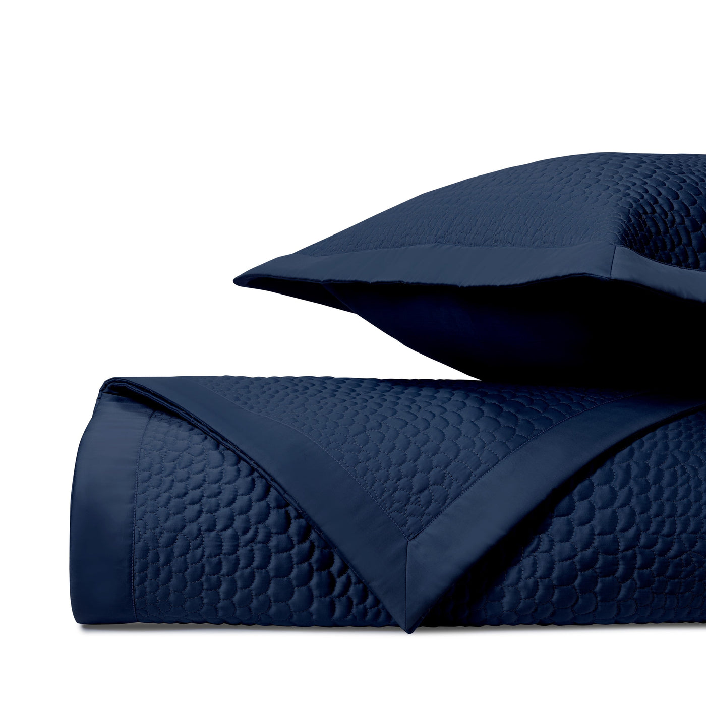 Close-up of navy blue quilted coverlet with geometric honeycomb stitching pattern.