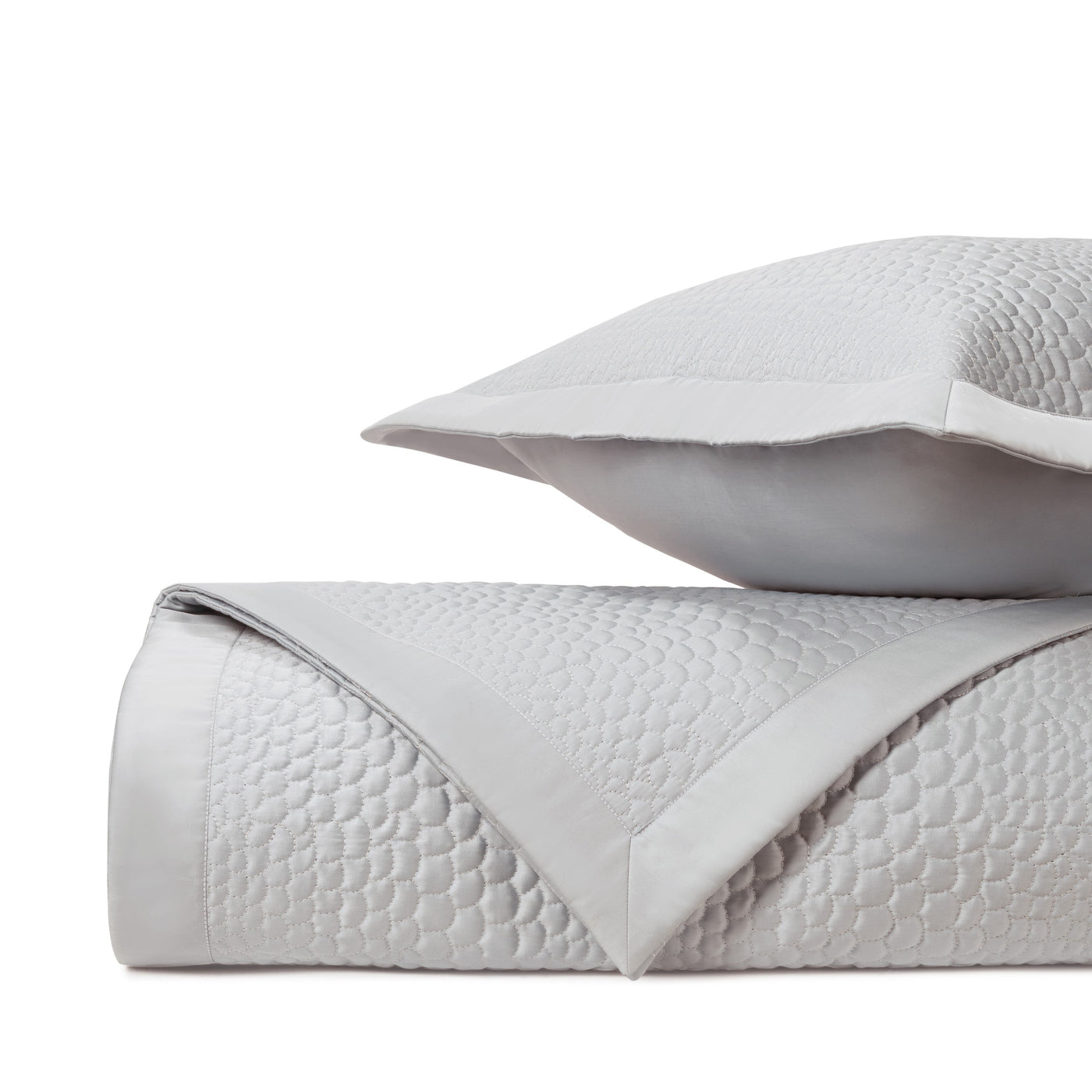 Close-up of Komodo quilted coverlet in silver with geometric honeycomb texture.