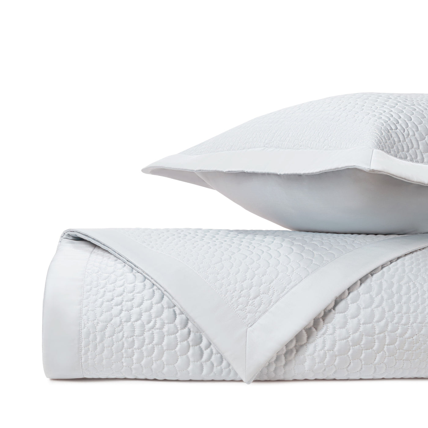 Close-up of white quilted honeycomb-pattern fabric with satin border detail.