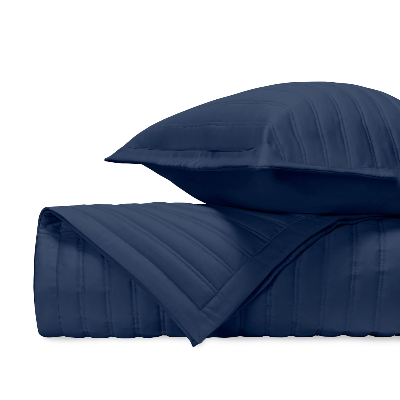 Close-up of navy quilted cotton sham and coverlet with parallel channel stitching.