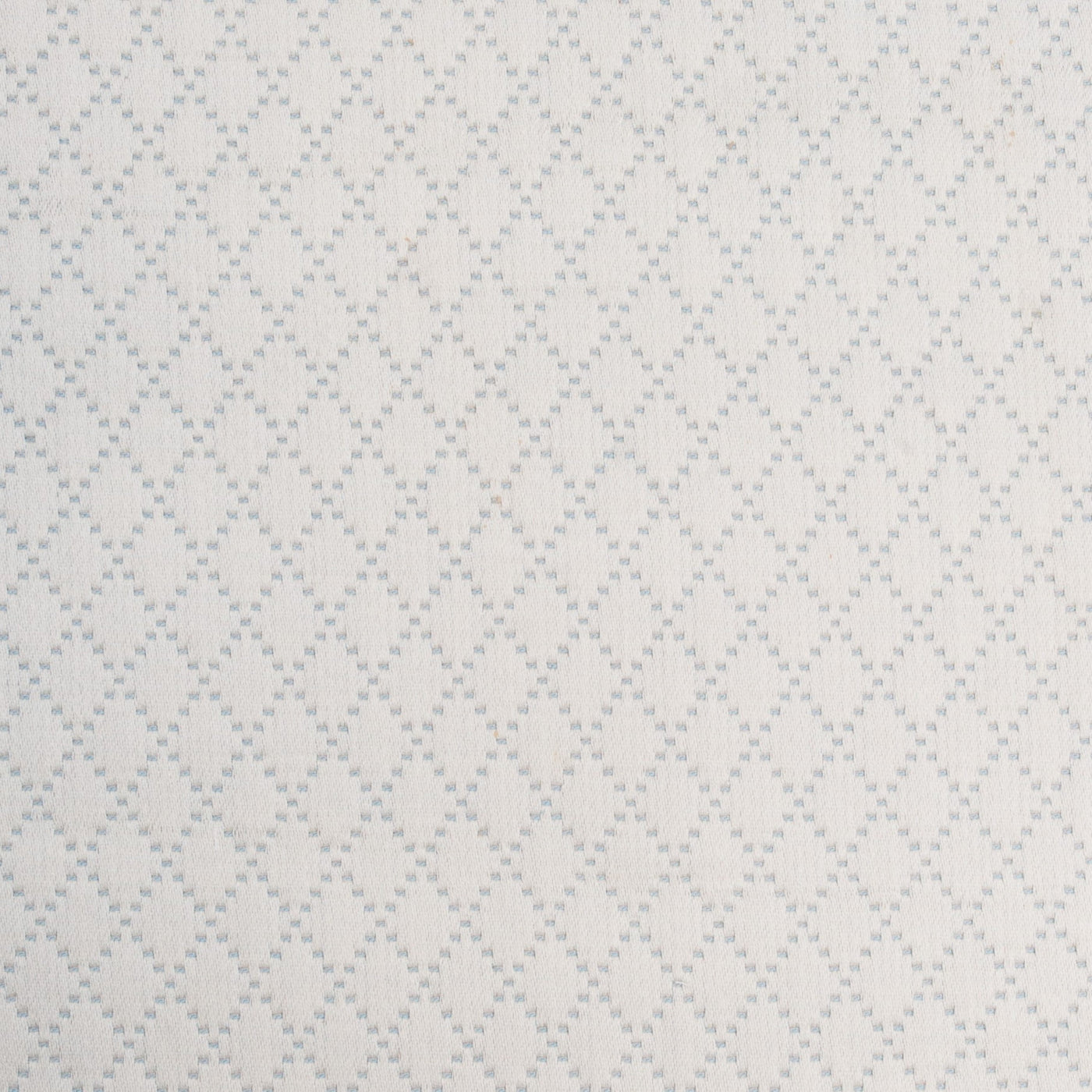 Close-up of ivory cotton coverlet with woven lattice diamond pattern.