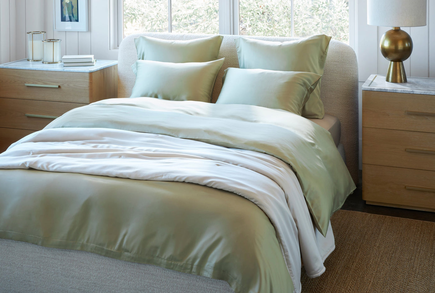 Legna Classic decorative pillow styled on a made bed with sage green bedding.